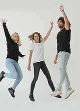 Drei Personen springen vor Freude während Sie Kleidung aus dem MPL-Shop präsentieren